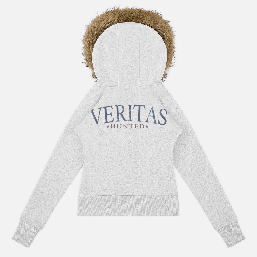 A light heather gray zip-up hoodie shown from the back, featuring a brown faux-fur trimmed hood and 'VERITAS HUNTED' printed in navy blue across the upper back.