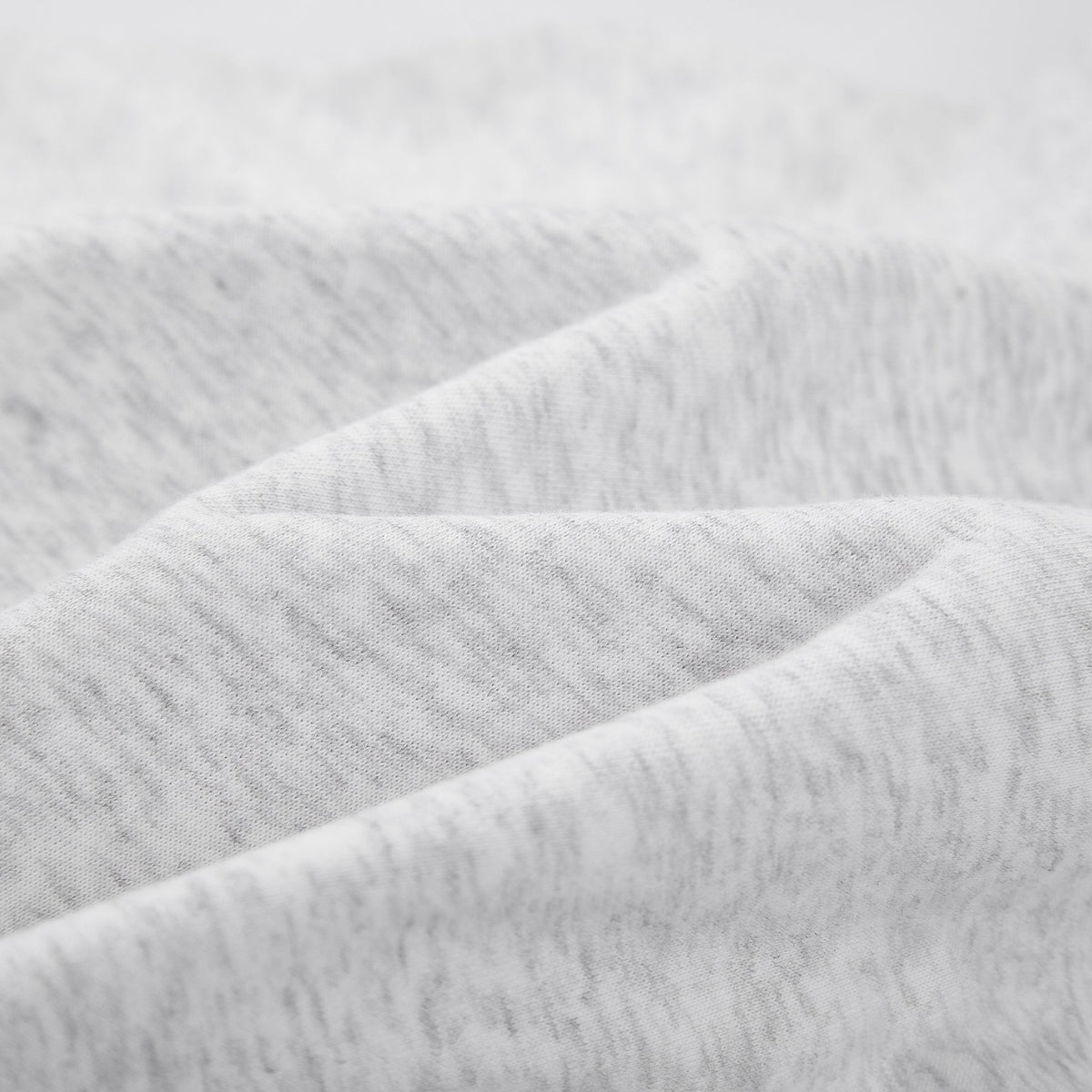 Close-up of light heather gray fabric with soft folds and a textured knit surface.