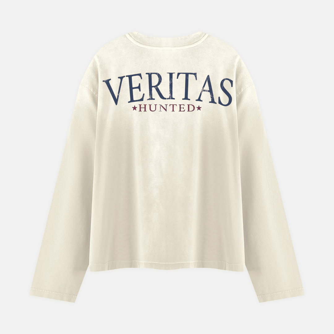 An off-white long-sleeve t-shirt with 'VERITAS HUNTED' printed in navy blue and burgundy on the back, displayed against a light gray background.