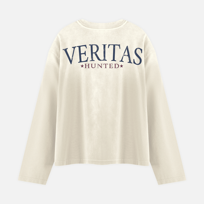 An off-white long-sleeve t-shirt with 'VERITAS HUNTED' printed in navy blue and burgundy on the back, displayed against a light gray background.