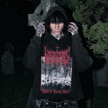 Person wearing a black hoodie with red and white graphic design in a dark, cemetery setting.